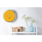 Sárga falióra geometrikus körcikkekkel és letisztult fekete számokkal modern stílusban