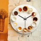  Kávés falióra kör alakban elrendezett porcelán csészékkel és kávékülönlegességekkel fehér háttérben